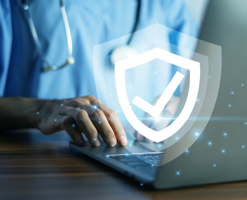 Doctor typing on a laptop with a glowing shield icon